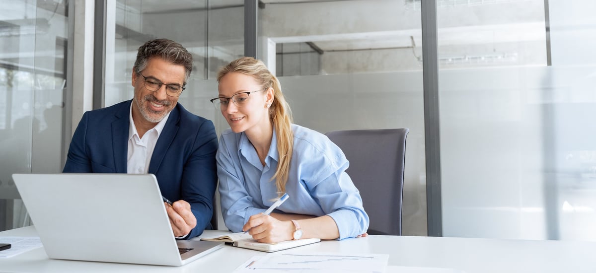 Mentor showing employee project on laptop